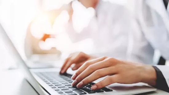 Un soigne tape sur un clavier d'ordinateur portable