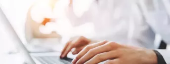 Un soigne tape sur un clavier d'ordinateur portable