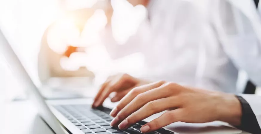 Un soigne tape sur un clavier d'ordinateur portable